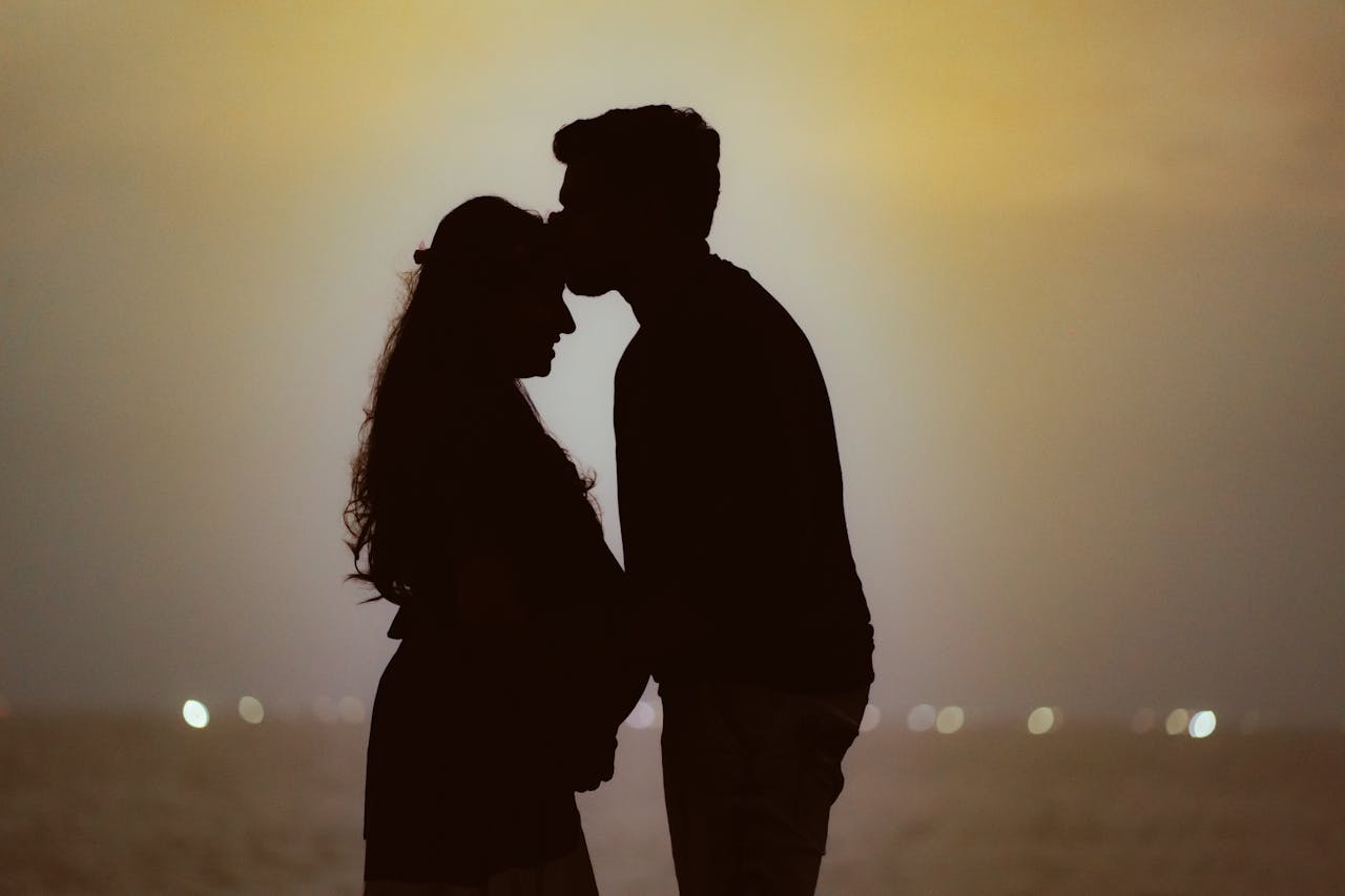 Silhouette of a couple at the beach celebrating motherhood during sunset.